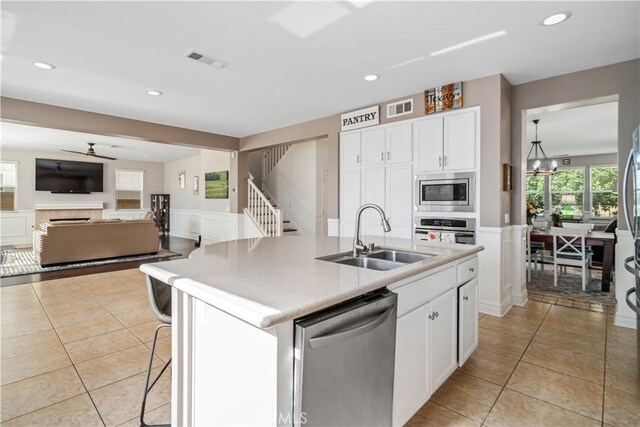 43145 62nd St W, Lancaster, CA 93536 - kitchen with appliances with stainless steel finishes, light tile patterned floors, white cabinets, a kitchen island with sink, and light countertops