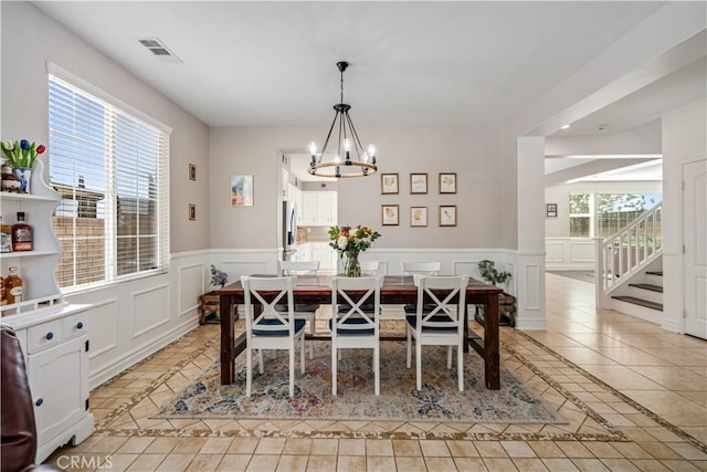 43145 62nd St W, Lancaster, CA 93536 - dining area featuring light tile patterned floors, a chandelier, inlaid floor details, a decorative wall, and wainscoting