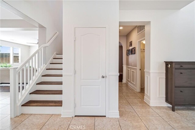 43145 62nd St W, Lancaster, CA 93536 - stairway featuring arched walkways, tile patterned floors, a decorative wall, and wainscoting