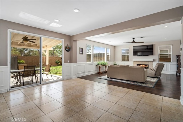 43145 62nd St W, Lancaster, CA 93536 - tiled living area with a decorative wall, ceiling fan, a lit fireplace, wainscoting, and recessed lighting