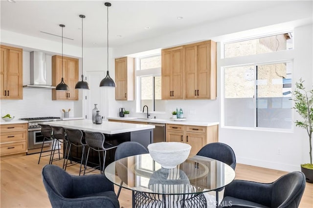 2102 Marshallfield Ln Unit B, Redondo Beach, CA 90278 - kitchen with wall chimney range hood, appliances with stainless steel finishes, light wood-type flooring, light countertops, and a breakfast bar