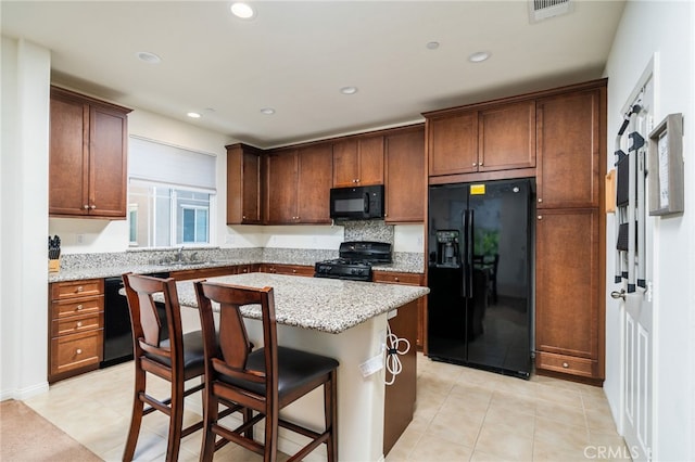 797 Plum Ln, Pomona, CA 91767 - kitchen featuring black appliances, a kitchen island, light stone counters, a breakfast bar area, and recessed lighting