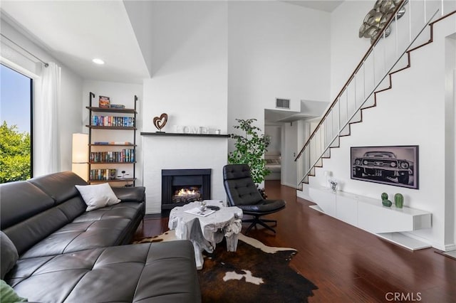 1237 E 6th St Unit 306, Long Beach, CA 90802 - living area with a lit fireplace, stairs, wood finished floors, and a towering ceiling