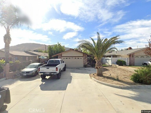 18145 10th St, Bloomington, CA 92316 - view of front of home featuring a garage, concrete driveway, a residential view, and a mountain view