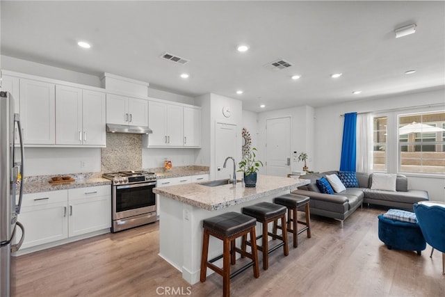 12062 Turnleaf Ave, Whittier, CA 90602 - kitchen featuring stainless steel appliances, a breakfast bar area, under cabinet range hood, open floor plan, and white cabinets
