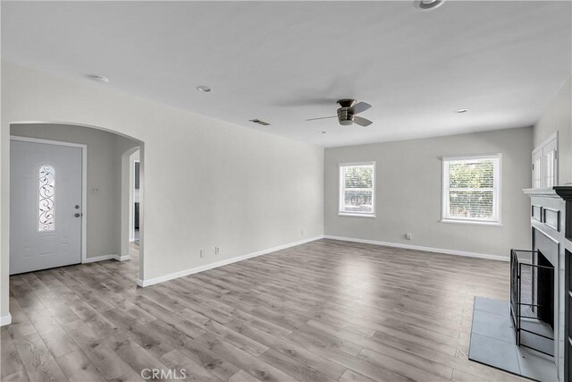 6017 Brockton Ave, Riverside, CA 92506 - unfurnished living room with arched walkways, a ceiling fan, a fireplace, and wood finished floors