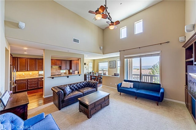 18956 Northern Dancer Ln, Yorba Linda, CA 92886 - living room with a ceiling fan, healthy amount of natural light, a glass covered fireplace, a towering ceiling, and light colored carpet