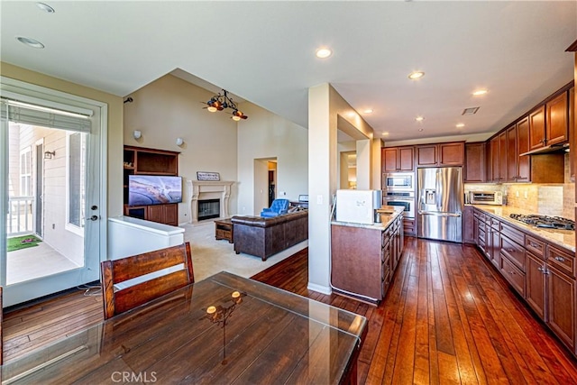 18956 Northern Dancer Ln, Yorba Linda, CA 92886 - kitchen with appliances with stainless steel finishes, a glass covered fireplace, dark wood-style flooring, tasteful backsplash, and recessed lighting