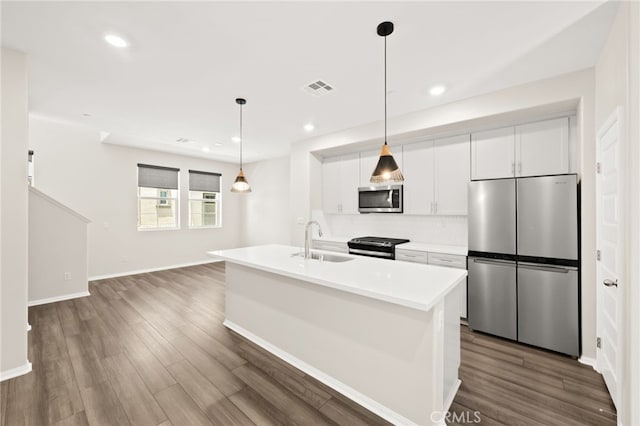 40497 Melrose Dr, Temecula, CA 92591 - kitchen featuring stainless steel appliances, white cabinets, light countertops, dark wood finished floors, and a kitchen island with sink