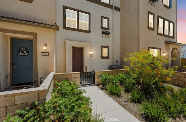 40497 Melrose Dr, Temecula, CA 92591 - exterior entry at dusk featuring stucco siding and a gate