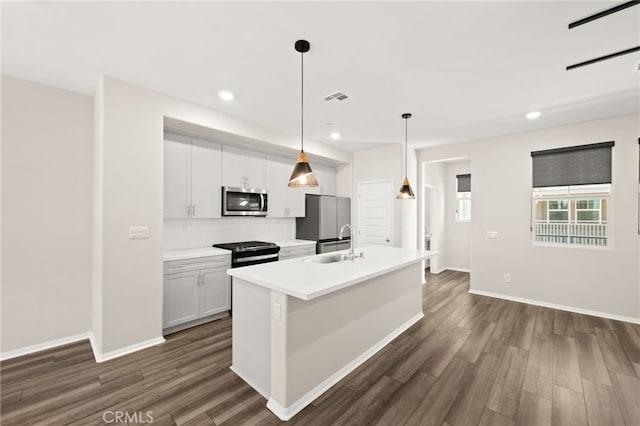 40497 Melrose Dr, Temecula, CA 92591 - kitchen featuring appliances with stainless steel finishes, dark wood finished floors, a kitchen island with sink, white cabinetry, and recessed lighting