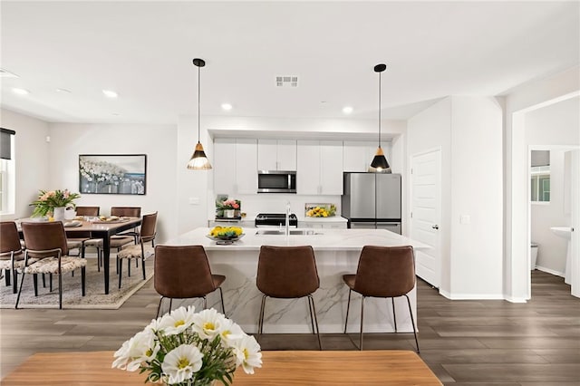 40497 Melrose Dr, Temecula, CA 92591 - kitchen with appliances with stainless steel finishes, white cabinets, dark wood finished floors, light countertops, and a kitchen bar