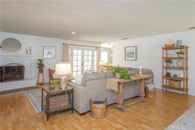 3360 Vanderbilt Ave, Turlock, CA 95382 - living room featuring light wood-style floors, a textured ceiling, a brick fireplace, recessed lighting, and french doors