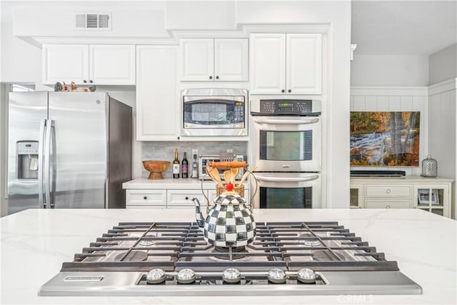 22681 Maplewood, Mission Viejo, CA 92692 - kitchen with appliances with stainless steel finishes, white cabinetry, light stone countertops, and backsplash