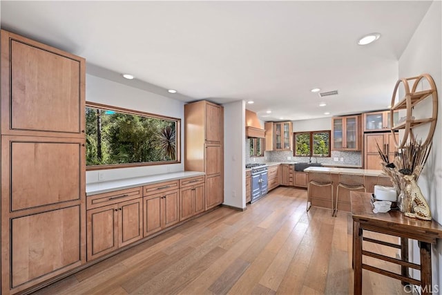 24537 Dry Canyon Cold Creek Rd, Calabasas, CA 91302 - kitchen featuring high quality appliances, a kitchen bar, light wood-style flooring, glass insert cabinets, and backsplash