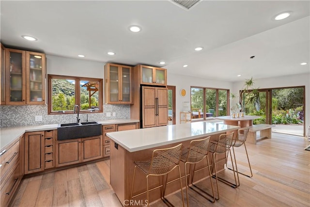 24537 Dry Canyon Cold Creek Rd, Calabasas, CA 91302 - kitchen featuring brown cabinetry, light wood finished floors, backsplash, a breakfast bar area, and recessed lighting