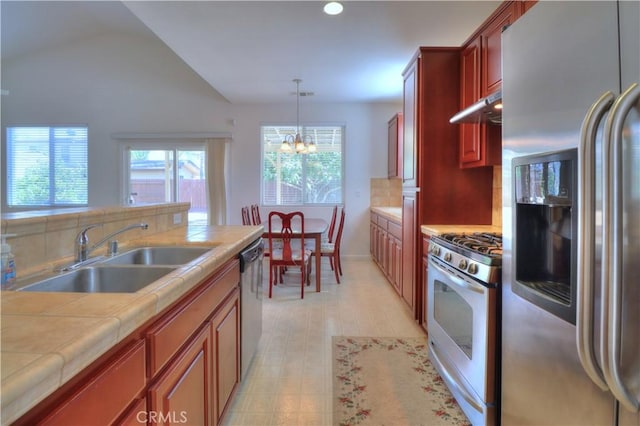 2062 Dunbar Way, Dinuba, CA 93618 - kitchen featuring appliances with stainless steel finishes, tile countertops, a chandelier, vaulted ceiling, and under cabinet range hood