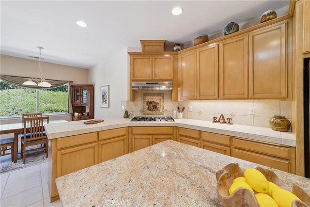 665 Silver Charm Dr, Arroyo Grande, CA 93420 - kitchen featuring under cabinet range hood, stainless steel gas cooktop, tasteful backsplash, light tile patterned floors, and a peninsula