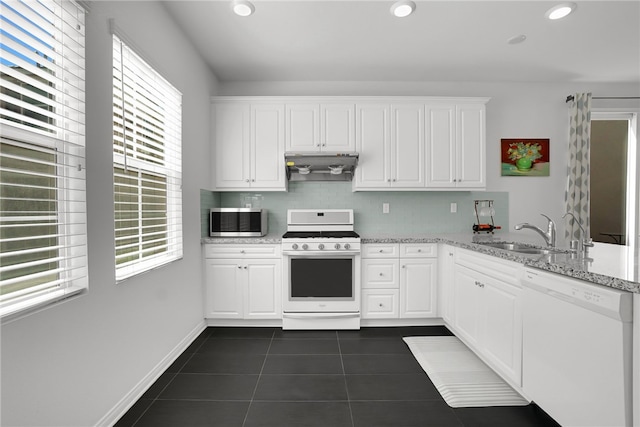 8595 Founders Grove St, Chino, CA 91708 - kitchen with white appliances, under cabinet range hood, dark tile patterned flooring, white cabinetry, and recessed lighting