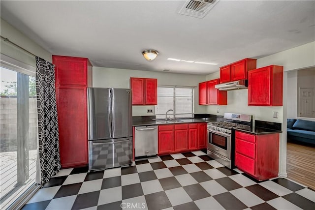 2917 Fairfield Ave, Palmdale, CA 93550 - kitchen with stainless steel appliances, reddish brown cabinets, dark flooring, and under cabinet range hood