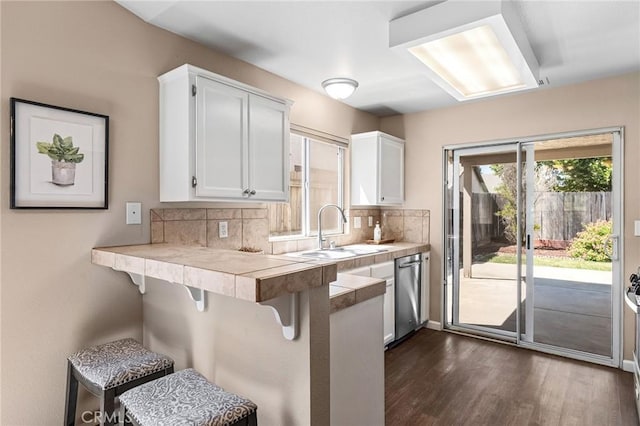2078 Mansfield Ct, Chico, CA 95928 - kitchen featuring dishwasher, a kitchen bar, decorative backsplash, white cabinets, and dark wood-style flooring