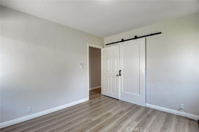 108 Chula St, Monrovia, CA 91016 - unfurnished bedroom featuring light wood-type flooring and a barn door