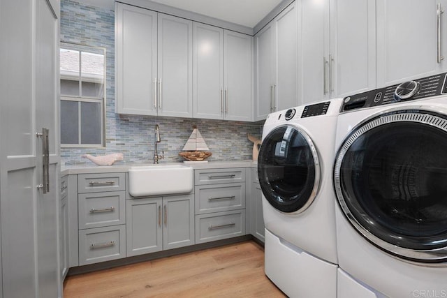 6925 Waters End Dr, Carlsbad, CA 92011 - laundry area with washer and clothes dryer, cabinet space, and light wood-style flooring
