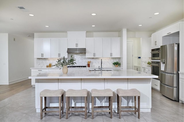 2415 Calle Grandon, Chula Vista, CA 91913 - kitchen featuring stainless steel fridge with ice dispenser, under cabinet range hood, a breakfast bar area, light tile patterned floors, and light countertops
