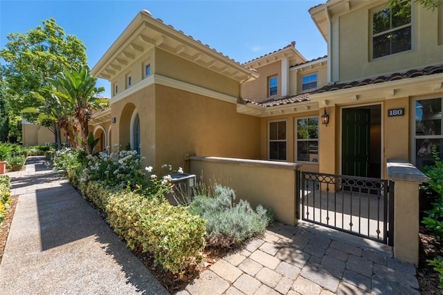 180 Guinevere, Irvine, CA 92620 - view of exterior entry featuring stucco siding, a gate, and a tiled roof
