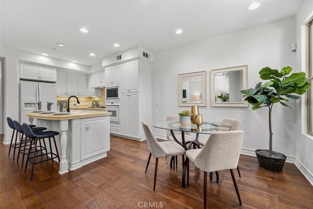 180 Guinevere, Irvine, CA 92620 - kitchen featuring white appliances, light countertops, a breakfast bar area, dark wood-style floors, and white cabinetry