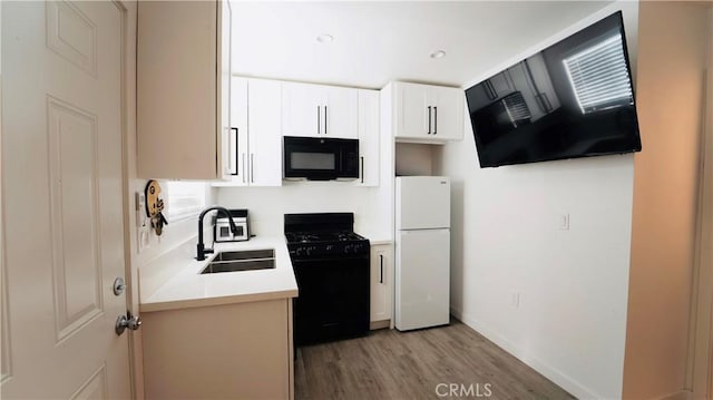 658 W 120th St, Los Angeles, CA 90044 - kitchen with black appliances, light wood finished floors, light countertops, white cabinetry, and exhaust hood