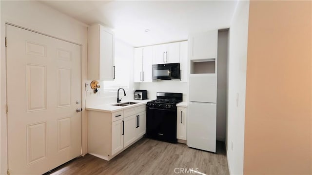 658 W 120th St, Los Angeles, CA 90044 - kitchen with black appliances, light wood-type flooring, white cabinetry, and light countertops