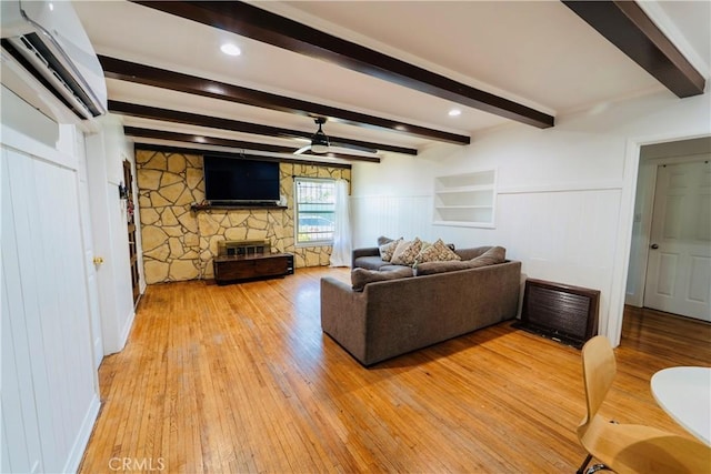 658 W 120th St, Los Angeles, CA 90044 - living room with a wall mounted AC, light wood-style flooring, a stone fireplace, a ceiling fan, and beamed ceiling