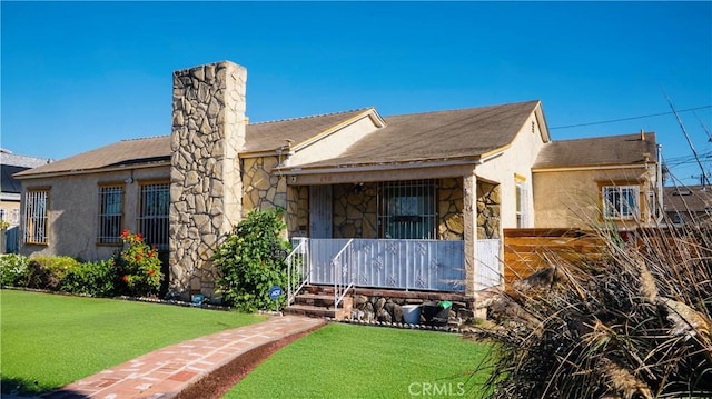 658 W 120th St, Los Angeles, CA 90044 - view of front of house with covered porch, stone siding, a chimney, and a front yard