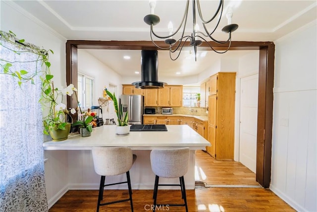 658 W 120th St, Los Angeles, CA 90044 - kitchen with stainless steel fridge with ice dispenser, light countertops, a chandelier, a peninsula, and light wood-style flooring