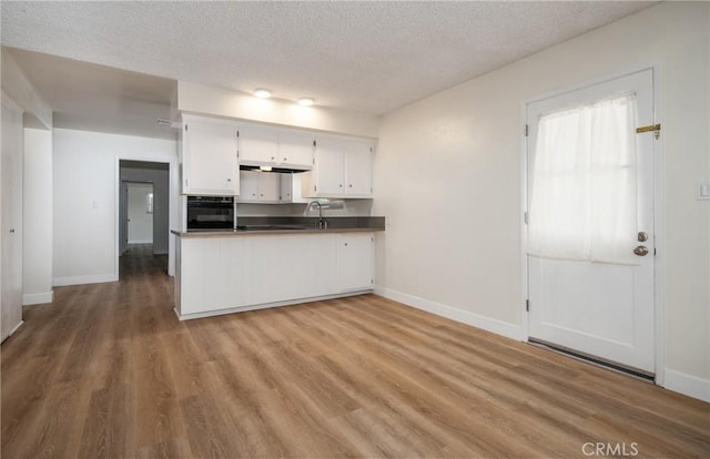 25070 Tulip Ave, Loma Linda, CA 92354 - kitchen featuring black oven, a textured ceiling, white cabinetry, wood finished floors, and a peninsula
