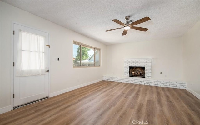 25070 Tulip Ave, Loma Linda, CA 92354 - unfurnished living room featuring a textured ceiling, a ceiling fan, wood finished floors, and a brick fireplace