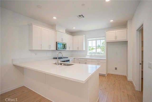 1239 Bonnet Way, Torrance, CA 90502 - kitchen featuring stainless steel microwave, light wood finished floors, a peninsula, white cabinetry, and recessed lighting