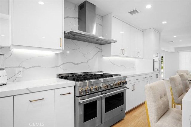 17437 Chase St, Northridge, CA 91325 - kitchen featuring range with two ovens, wall chimney exhaust hood, white cabinets, light stone counters, and recessed lighting