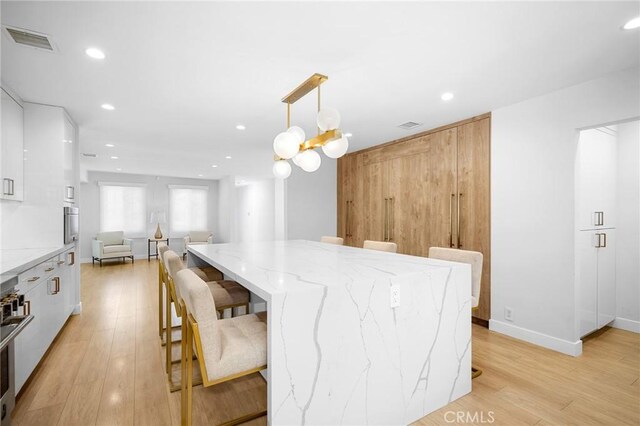 17437 Chase St, Northridge, CA 91325 - kitchen featuring modern cabinets, light wood-style floors, a kitchen bar, white cabinetry, and recessed lighting