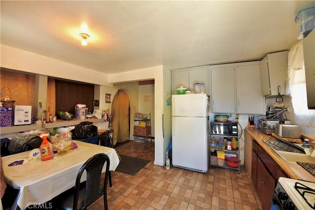 3945 Woolwine Dr, Los Angeles, CA 90063 - kitchen with white appliances, arched walkways, brick patterned flooring, and light countertops