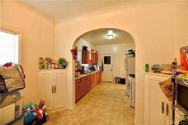 3945 Woolwine Dr, Los Angeles, CA 90063 - kitchen featuring arched walkways, light tile patterned floors, light countertops, and brown cabinetry