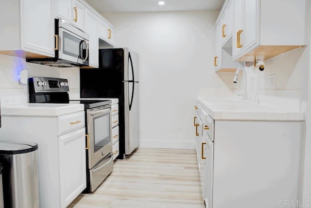 2041 E Grand Ave E Unit 3, Escondido, CA 92027 - kitchen with appliances with stainless steel finishes, tile countertops, light wood-style flooring, white cabinetry, and recessed lighting