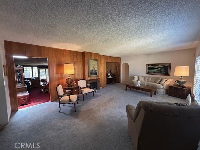 1220 W L St, Wilmington, CA 90744 - living area featuring arched walkways, a textured ceiling, wooden walls, and carpet