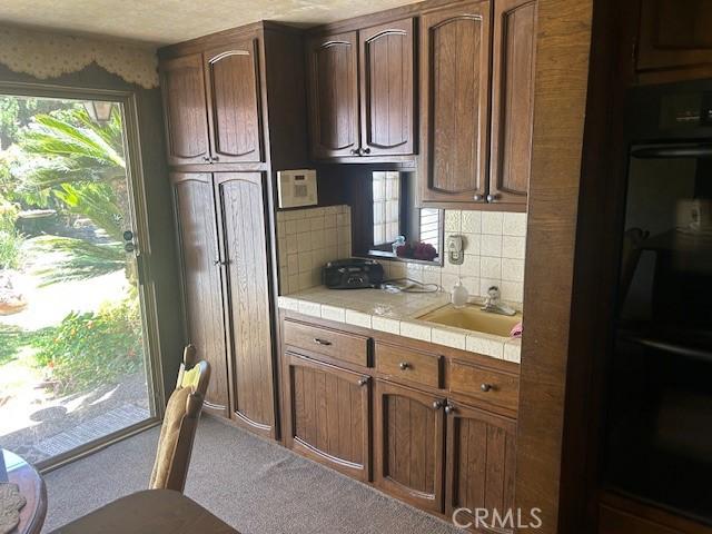 1220 W L St, Wilmington, CA 90744 - kitchen featuring tile counters, carpet, plenty of natural light, and backsplash