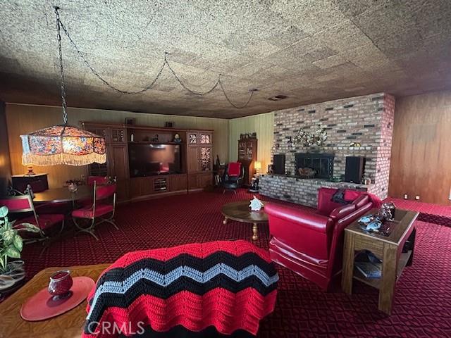 1220 W L St, Wilmington, CA 90744 - living area featuring carpet floors, wood walls, and a fireplace