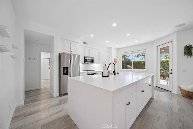 21 Dawnwood, Ladera Ranch, CA 92694 - kitchen featuring stainless steel appliances, light wood-style floors, white cabinets, a center island with sink, and light countertops