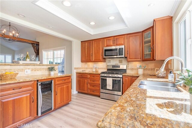 24046 Lindley St, Mission Viejo, CA 92691 - kitchen with wine cooler, appliances with stainless steel finishes, brown cabinetry, light stone counters, and backsplash