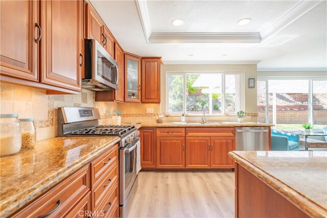 24046 Lindley St, Mission Viejo, CA 92691 - kitchen with stainless steel appliances, brown cabinetry, light wood-style floors, light stone countertops, and decorative backsplash