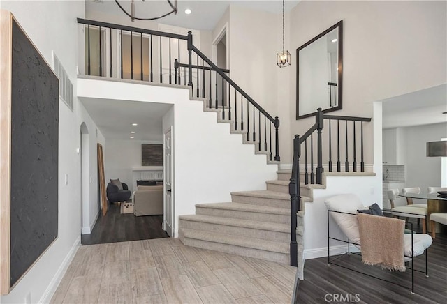 24532 La Cienega St, Laguna Hills, CA 92653 - staircase featuring a towering ceiling, wood finished floors, a chandelier, recessed lighting, and arched walkways